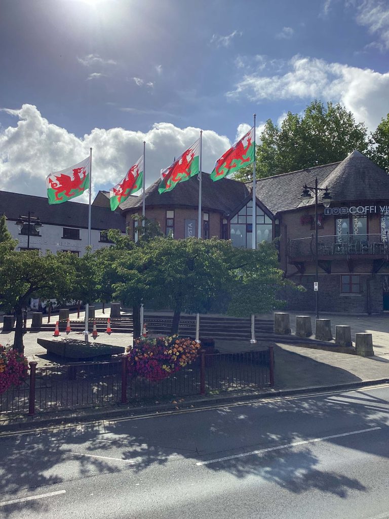 caerphilly visitors centre with four architectural flagpoles displaying the Welsh dragon flag