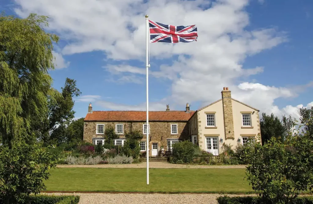 A garden flagpole flying in front of a home, displaying the Union flag