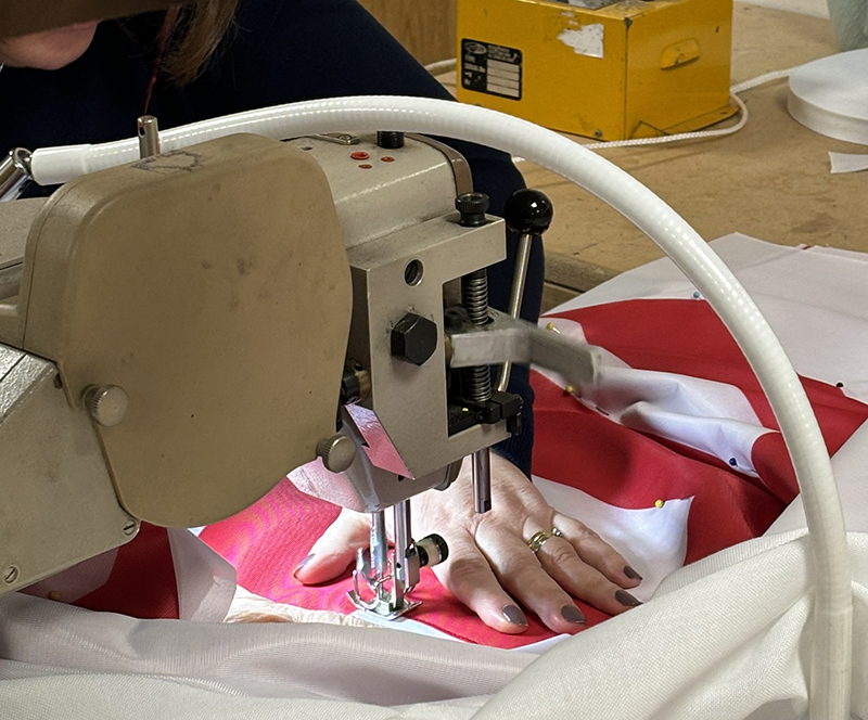Red and white flag being hand-sewn